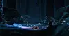 Small glowing object on a reflective dark surface with blue light streaks in a dim scene.