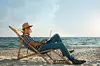 Man working with laptop in deck chair on beach