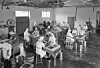 People sorting and packing berries at tables in a large, simple building with buckets and crates.