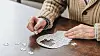 Cropped view of a senior man placing jigsaw puzzle pieces on a table.
