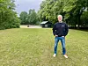 Man standing on a field with trees in the background.