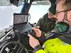 Two archaeologists in a vehicle review live scan data on a laptop and monitor.
