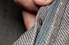 Nærbilde av et veggedyr i en madrasssøm som holdes åpen med en finger.