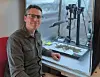 James Speed sits at a desk beside scientific equipment and research papers.
