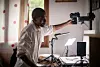 Eric Rakotoniaina works beside a camera and monitor at a botanical digitisation workstation.