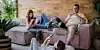 Family members relax together on and around a sofa in a warmly furnished living room.