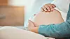 Hands resting on a pregnant abdomen, illustrating research into gestational diabetes risk.