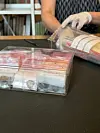 A plastic box full of plastic bags, each containing a coin.