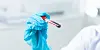 Blue-gloved laboratory worker holding a blood collection tube in a clinical research setting.