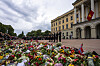 Et stort blomsterhav foran Slottet i Oslo, med norske flagg og sørgende besøkende.