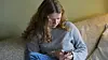 Young person sitting on a sofa and looking at a smartphone