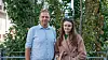 Joachim Kjennerud and Marita Skjuve standing together outdoors among leafy trees.