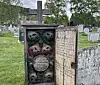Headstone with carved decorations and an open panel in a Vågå cemetery.
