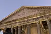 Close view of the Pantheon’s stone pediment, Latin inscription and classical columns against a clear blue sky.
