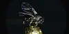 Metallic winged insect above a sparkling gold surface on a black background