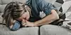 Person lying on a sofa with their head in their hands, illustrating migraine-related discomfort.