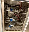 Lithium-ion batteries and wiring arranged on shelves inside a climate-controlled testing chamber.