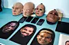Lifelike silicone masks and printed faces arranged beside smartphones and tablets on a table.