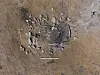 Close-up of a rectangular structure surrounded by stones in brown soil.