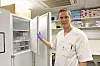 Healthcare worker in scrubs opening a cabinet of medicines and medical supplies.