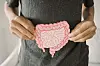 Man holding a pink anatomical model of the human colon against a dark shirt