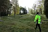 Woman in high-visibility clothing walking across a grassy slope.