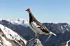 Male rock ptarmigan perched on a rock above snow-dusted mountains in Japan.