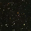 Dense deep-space field filled with distant galaxies and stars on a black background.