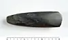 Dark elongated stone artefact positioned above a metric ruler on a plain background.
