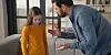 Father gesturing towards his adolescent daughter during a tense conversation at home.